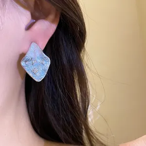 Macro detail view of elegant wrinkled diamond stud earrings with sparkling zircon inlays