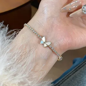 Primo piano di uno squisito bracciale a farfalla placcato oro 18k con zirconi su un polso.