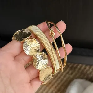 Close-up of a stylish gold metal geometric bracelet set held in hand for detail