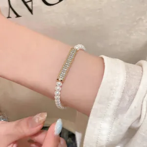 Close-up detail view of an elegant zircon and pearl bracelet worn on a woman's wrist.