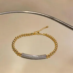 Elegant gold beaded bracelet featuring a silver curved bar set with sparkling zircon stones