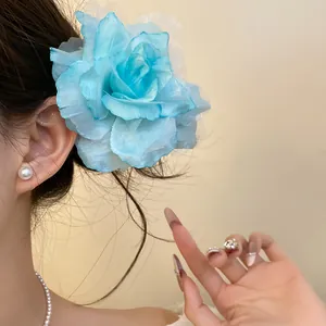 Detail view showing a large blue fabric mesh flower hair clip worn on a side bun