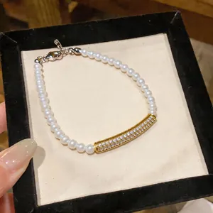 Detailed close-up shot of a pearl bracelet featuring a gold curved bar with pavé zircons.
