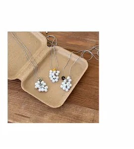 Detailed macro view of three pearl grape cluster necklaces displayed in eco-friendly packaging