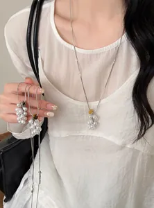 Close-up of pearl grape cluster pendant necklaces with natural stone accents on a model