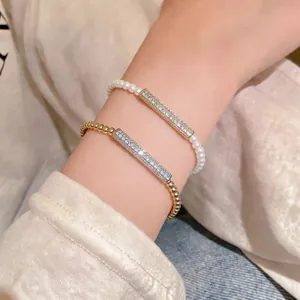 Close-up of elegant zircon bar bracelets with pearls and golden beads on wrist