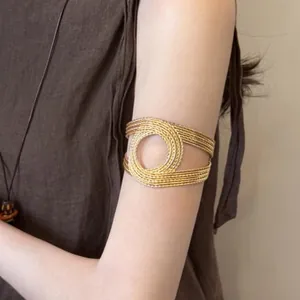 Detailed view of a geometric gold circular arm cuff bracelet with elegant wire-wrap texture