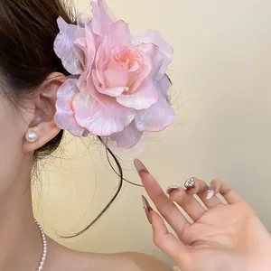 Detailed view of an elegant pink mesh fabric rose hair clip on a model's styled hair.