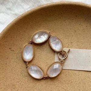 Close-up of a gold-toned bracelet featuring five faceted oval stones and a toggle clasp.