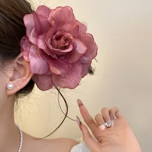 Close-up view of an elegant mauve gauze flower hair clip worn by a model in warm light