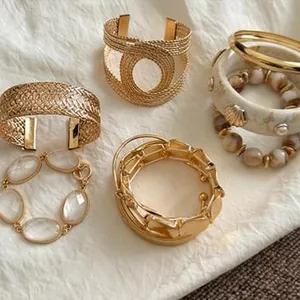Close-up display of bohemian gold-tone geometric metal bracelets and neutral beaded bangles