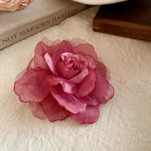 Close-up of a handmade dusty pink mesh fabric rose flower hair clip on soft fabric