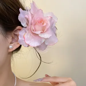 Detail showing a large pink mesh flower hair clip worn by a model in soft lighting