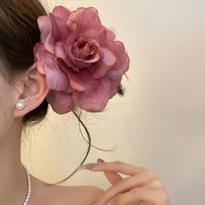Side view of a large dusty rose fabric flower hair clip worn by an elegant model.