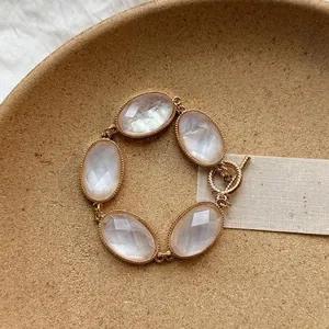 Elegant gold-tone bracelet featuring faceted oval moonstone-like stones in a minimalist design.