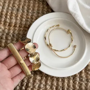 Macro view of vintage gold layered bracelets and stylish twisted open cuff bangles
