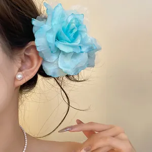 Elegant light blue mesh flower hair clip worn by a model for a stylish vacation look.