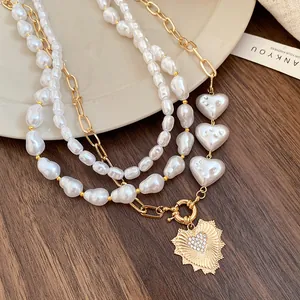 Primer plano de collar de perlas barrocas de varias capas con colgante de corazón de oro texturizado