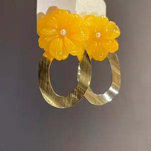Macro di orecchini a fiore in resina gialla con pendenti ovali dorati e perni in argento