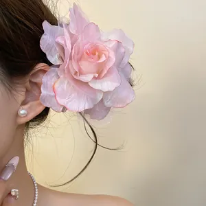 A detailed view showing an elegant pink mesh rose flower hair clip worn by a model.