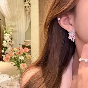 Elegante Nahaufnahme von süßen rosa Schleifenohrringen mit Zirkonia am Modell