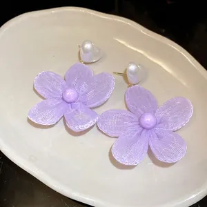 Sweet purple camellia flower pendant earrings with white heart studs on a white plate