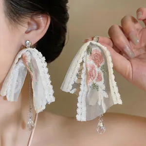 Close-up of elegant lace flower earrings with crystal water drop tassels