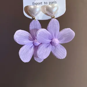 Detailed macro view of purple mesh camellia dangle earrings with white heart studs