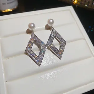 Elegant sparkling rhombus stud earrings with a white pearl top displayed on a white tray