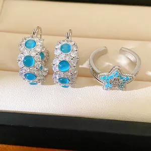 Detail view of blue cat's eye earrings and star ring set with cubic zirconia stones.