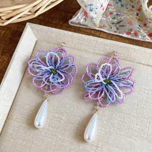 Gros plan sur des boucles d'oreilles fleurs en perles avec perles en goutte.