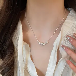 Detailed view of a minimalist silver necklace featuring irregular beads worn by a model