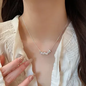 Detailed view of a minimalist silver necklace with stylish irregular pendants worn on a model