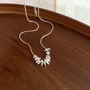 Detailed macro shot of minimalist silver necklace with irregular pendants on dark wood