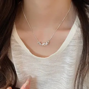 Close-up view of a minimalist silver irregular pendant necklace worn on a model's neck