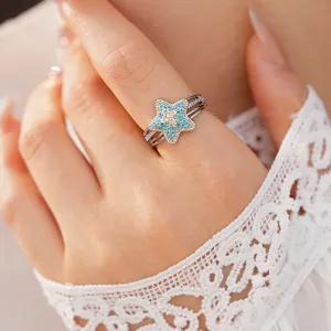 Macro view of a silver ring with a blue star-shaped charm and sparkling pavé stones.