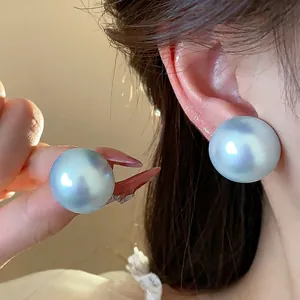 Elegantes pendientes de perlas azul irisado de estilo francés usados y sostenidos