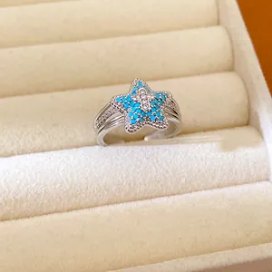 Close-up detail of a silver starfish ring with blue stones and zircon inlay in a box