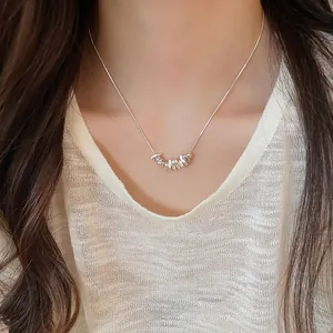 Detailed view of a minimalist silver necklace with irregular pebble pendants on a model.