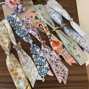 Detailed view of various floral and polka dot skinny scarves with decorative metallic slides