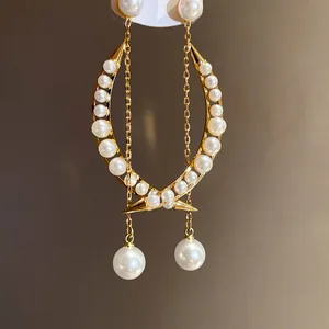 Gros plan de boucles d'oreilles lune élégantes avec perles blanches et glands dorés