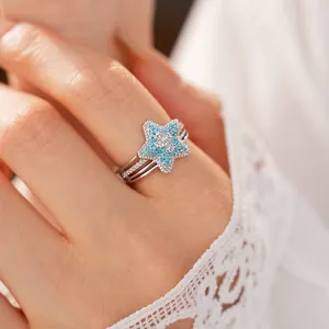 Close-up of an elegant silver star-shaped ring featuring blue beads and zircon cross detail
