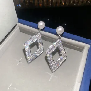 Close-up view of geometric rhombus diamond earrings with pearl studs
