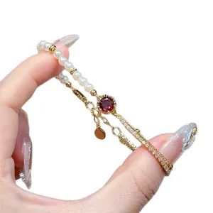 Elegant 18K gold plated adjustable bracelet with pearls and red zircon, held by hand