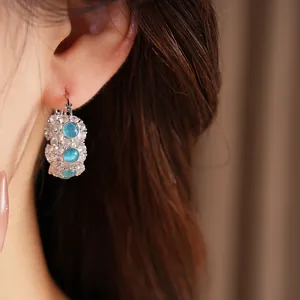 Close-up detail of luxurious blue cat's eye hoop earrings with sparkling cubic zirconia