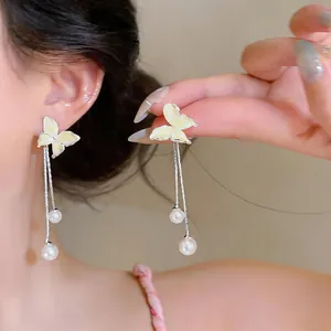 Close-up detail of elegant butterfly tassel earrings featuring delicate white pearls.