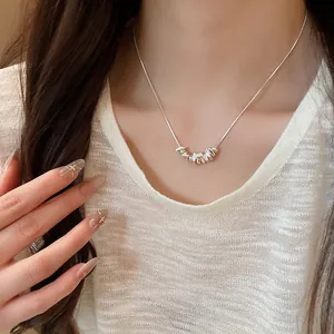 Close-up detail of minimalist silver necklace featuring irregular pendant beads on model