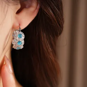 Close-up of blue cat's eye stone hoop earrings with sparkly cubic zirconia on ear.