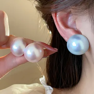 Detalle de pendientes de perlas iridiscentes grandes con estilo minimalista