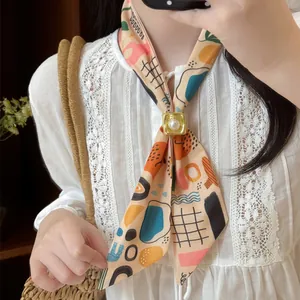 Detail of a colorful patterned skinny scarf with a pearl-inlaid gold buckle accessory.